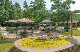 A patio with several tables and chairs, some with umbrellas, is set up for outdoor dining. AI generated content