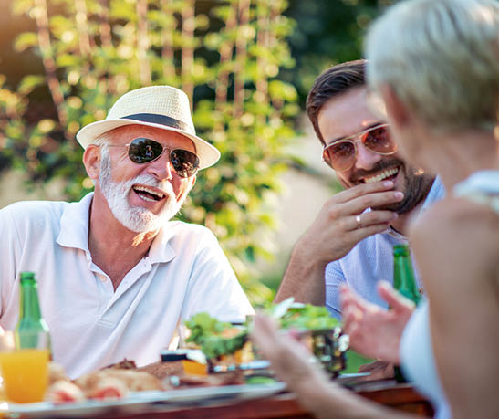 Two generations of family gathered to picnic in the garden on sunny day.